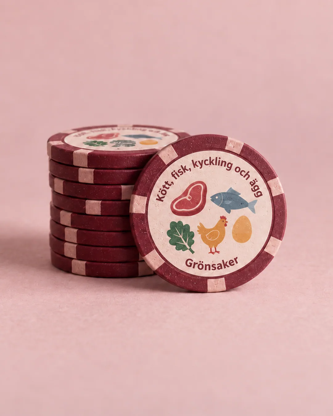 Stack of burgundy poker chips on a pink background, where the front chip shows meat, fish, chicken, eggs and vegetables, symbol for All in