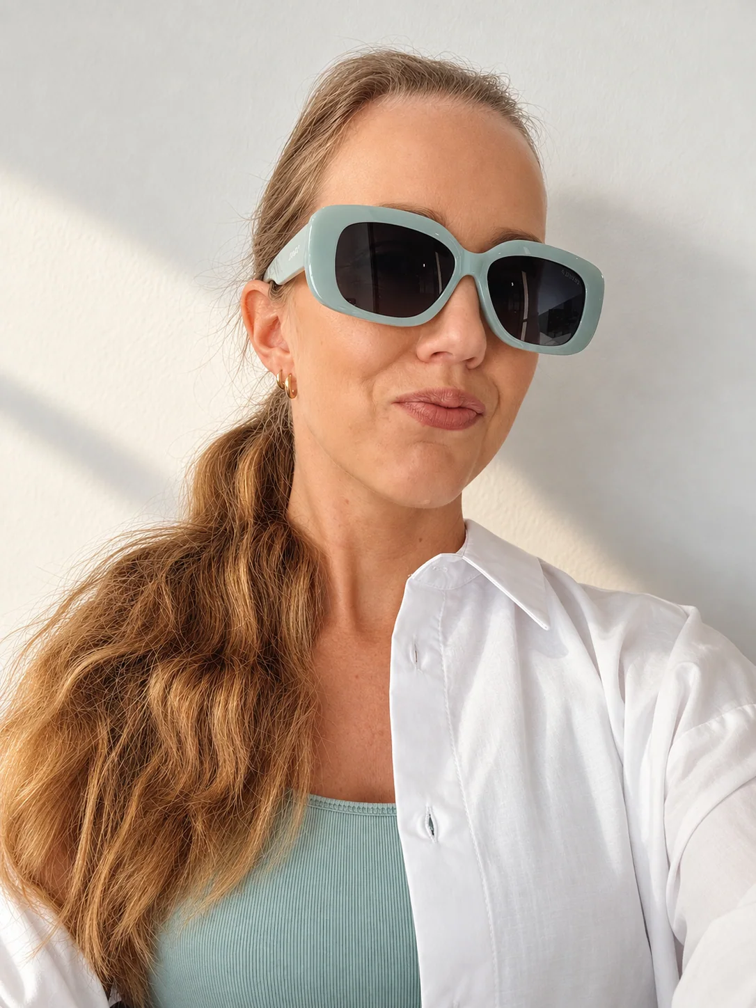 Marie Wasserman, health coach, in a white shirt and turquoise sunglasses